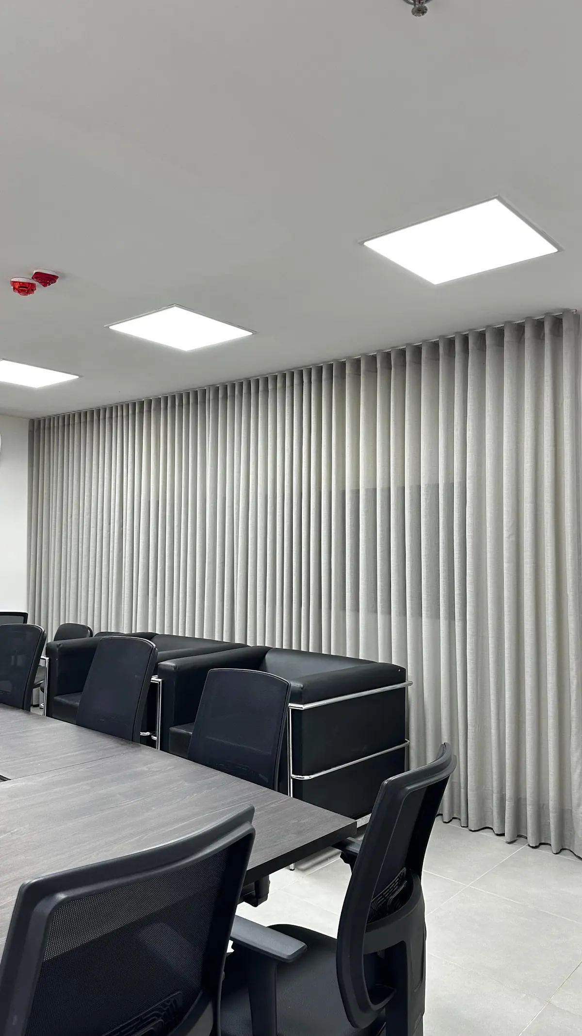 Sala de reuniones con mesa negra y cortinas verticales