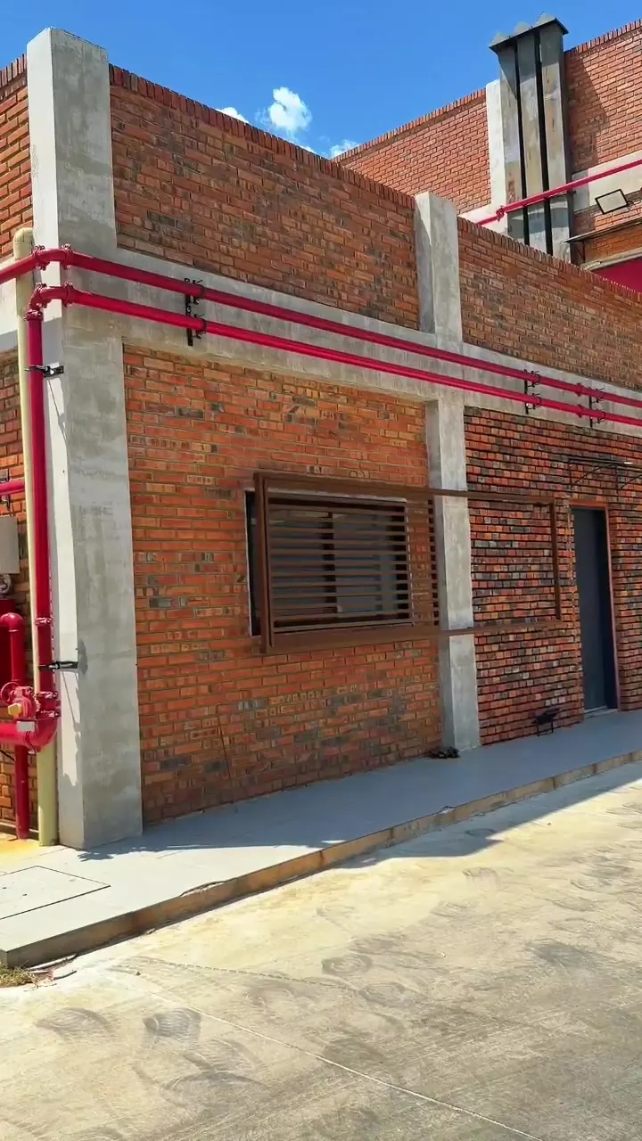 Lateral del edificio con cañería de incendio y ventanas con celosía